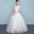 Woman wearing a white wedding dress with floral lace details on a gray background