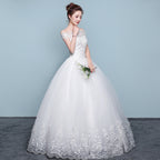 Woman wearing a white wedding dress with floral details on a plain background