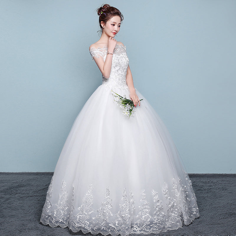 Woman wearing a white wedding dress with floral details on a plain background