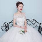 Woman in a white wedding dress holding flowers against a light blue background