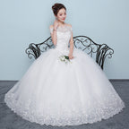 Woman in a white wedding dress sitting on a black iron bench against a light blue wall.