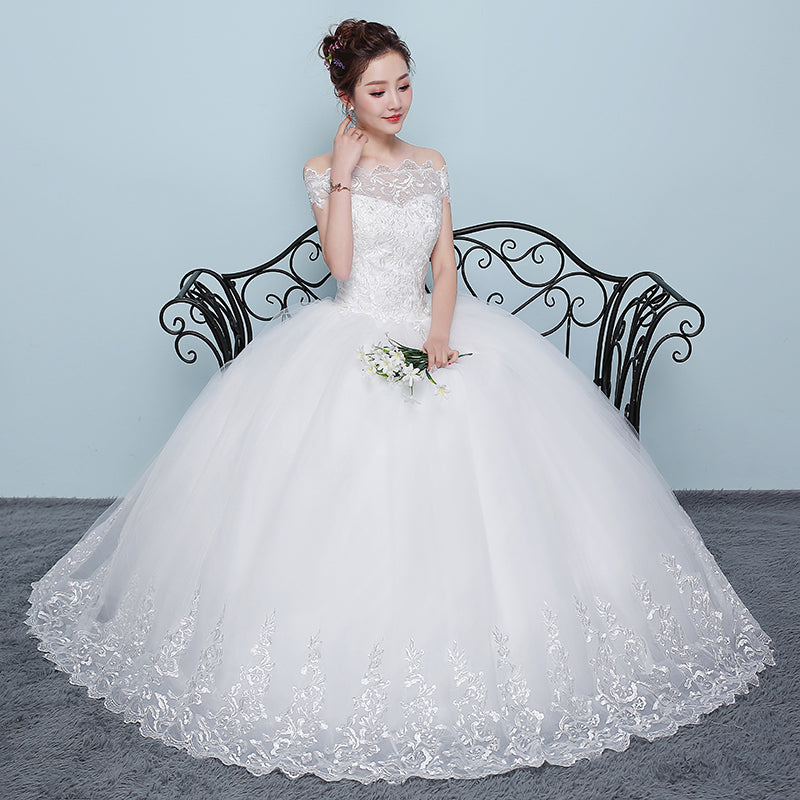 Woman in a white wedding dress sitting on a black iron bench against a light blue wall.