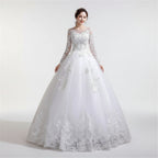 Woman wearing a white lace wedding dress against a textured wall.