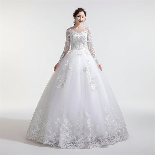 Woman wearing a white lace wedding dress against a textured wall.
