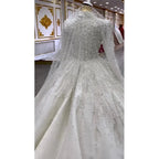 Elegant white wedding dress with intricate detailing on a mannequin in a store setting.
