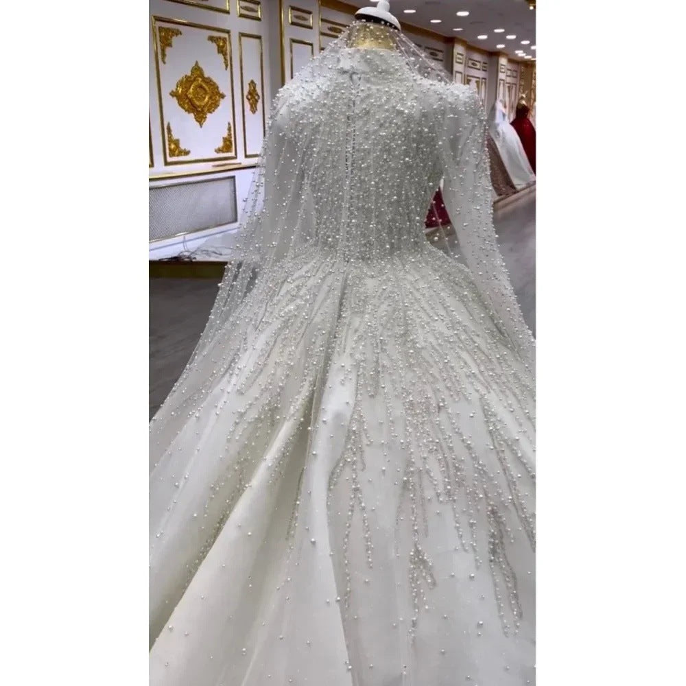 Elegant white wedding dress with intricate detailing on a mannequin in a store setting.