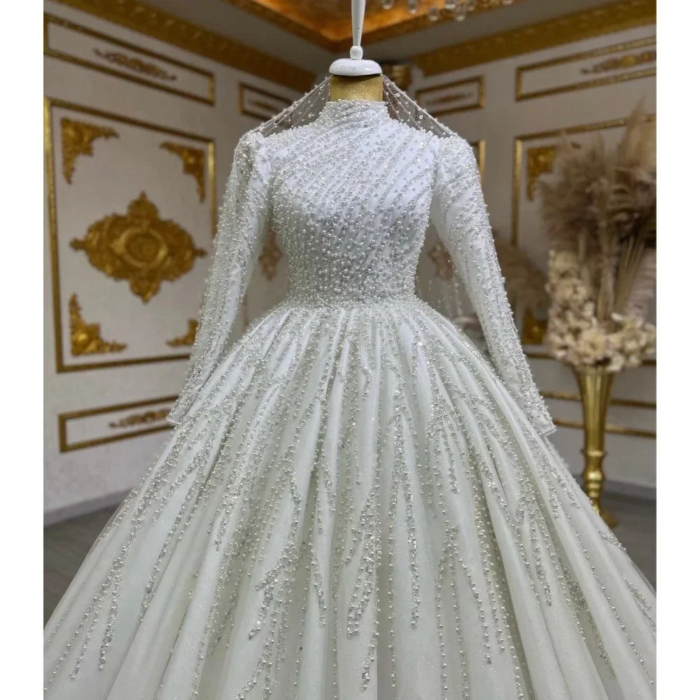 Elegant silver beaded gown on a mannequin against an ornate wall.