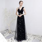 Woman wearing a black evening gown with floral embroidery on a white background