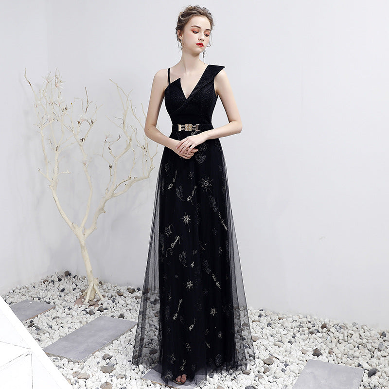 Woman wearing a black evening gown with floral embroidery on a white background