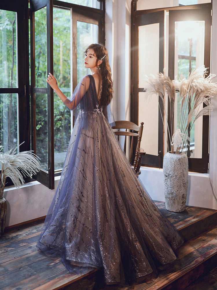 Woman in a sparkly dress standing in a room with large windows and decorative plants.
