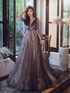 Woman in a long, elegant dress standing indoors with large windows in the background.