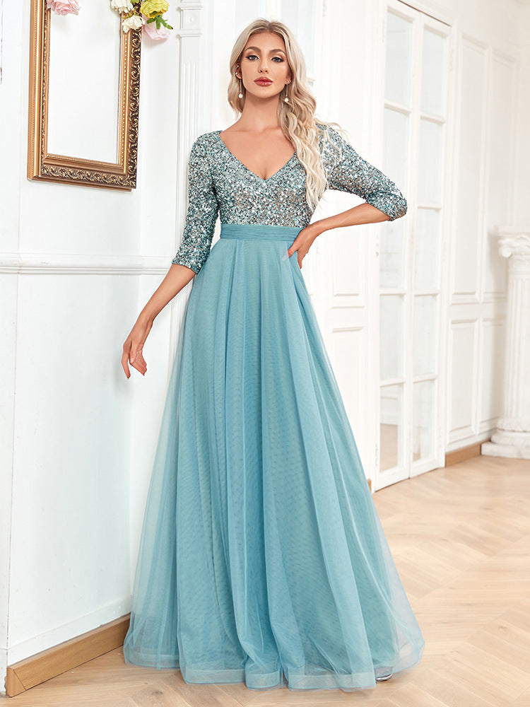 Woman wearing a blue evening gown with silver sequin top in a room.