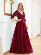 Woman wearing a burgundy evening gown with sequin top in a room.