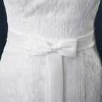White lace dress with a bow detail on a dark background