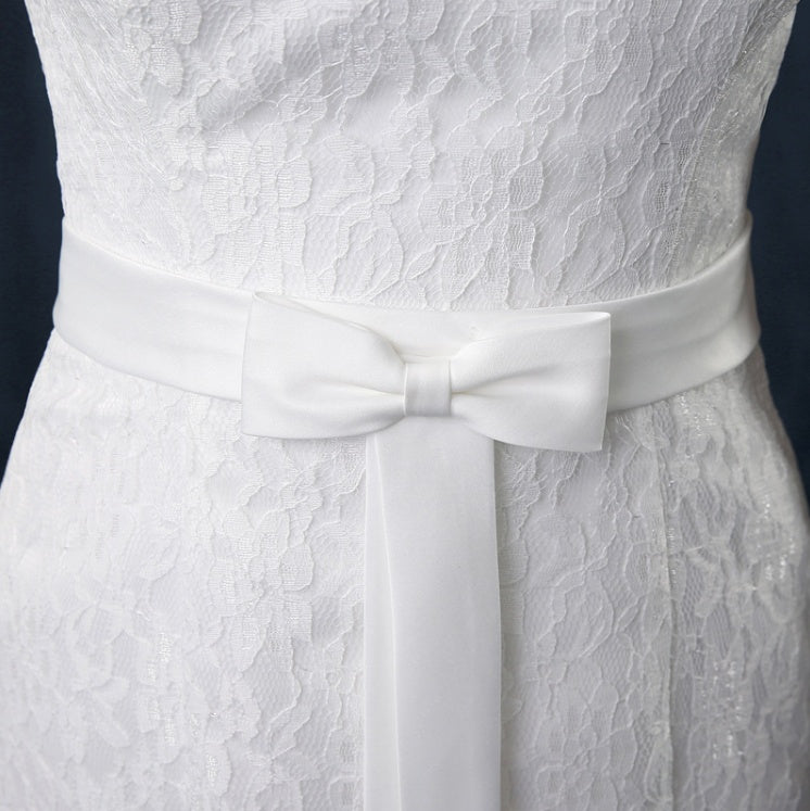 White lace dress with a bow detail on a dark background