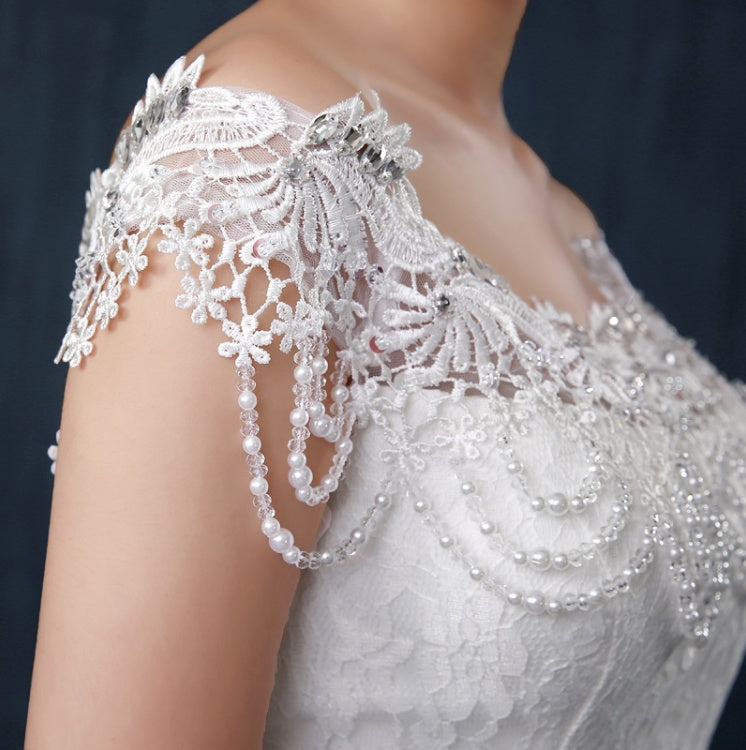 Close-up of a white lace and pearl shoulder detail on a garment.