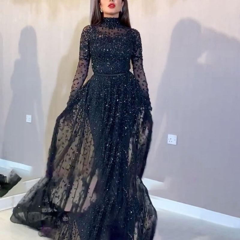 Black sheer evening gown with long sleeves and a flowing skirt on a neutral background