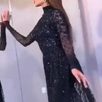 Person wearing a black sequin dress against a neutral background