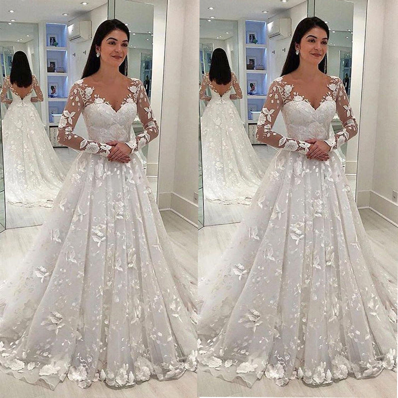 Woman in a white floral wedding dress standing in front of a mirror.