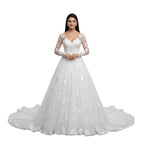 Woman wearing a white wedding dress with floral details in a mirror reflection.