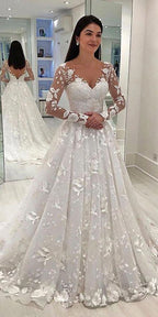 Woman wearing a white wedding dress with floral details in a mirror reflection.