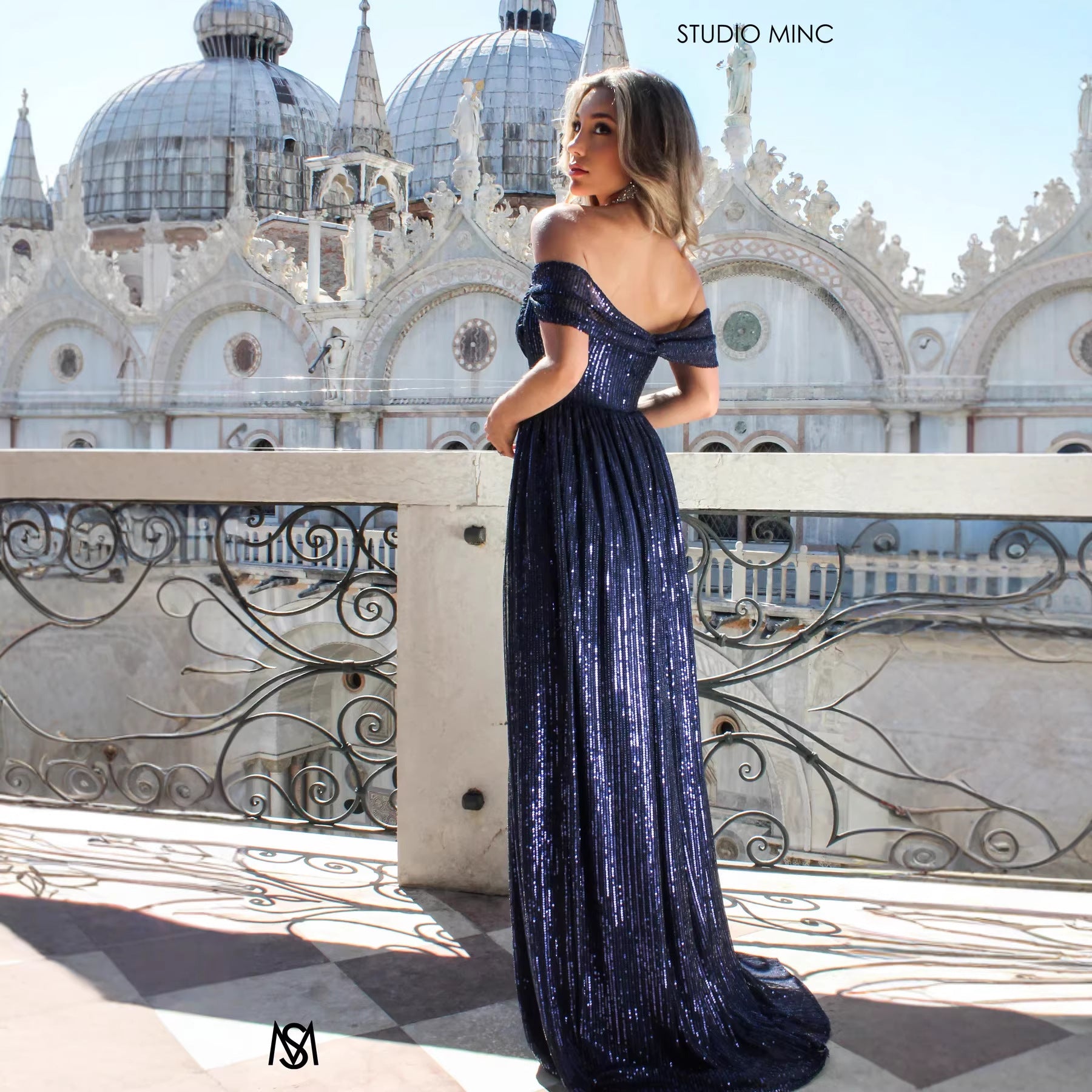 Woman in a blue evening gown standing in front of an ornate building with domes.