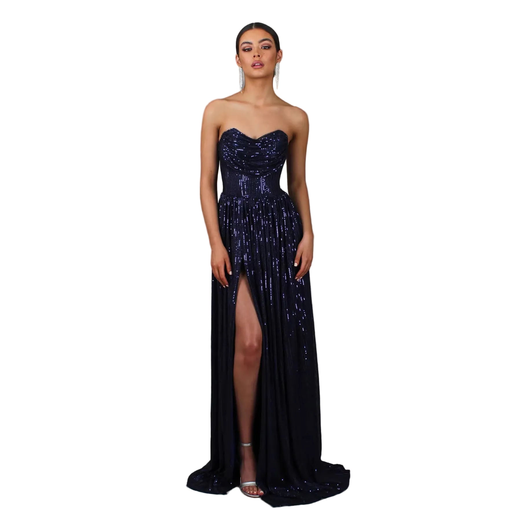 Woman wearing a strapless, sequined evening gown with a high slit on a gray background.