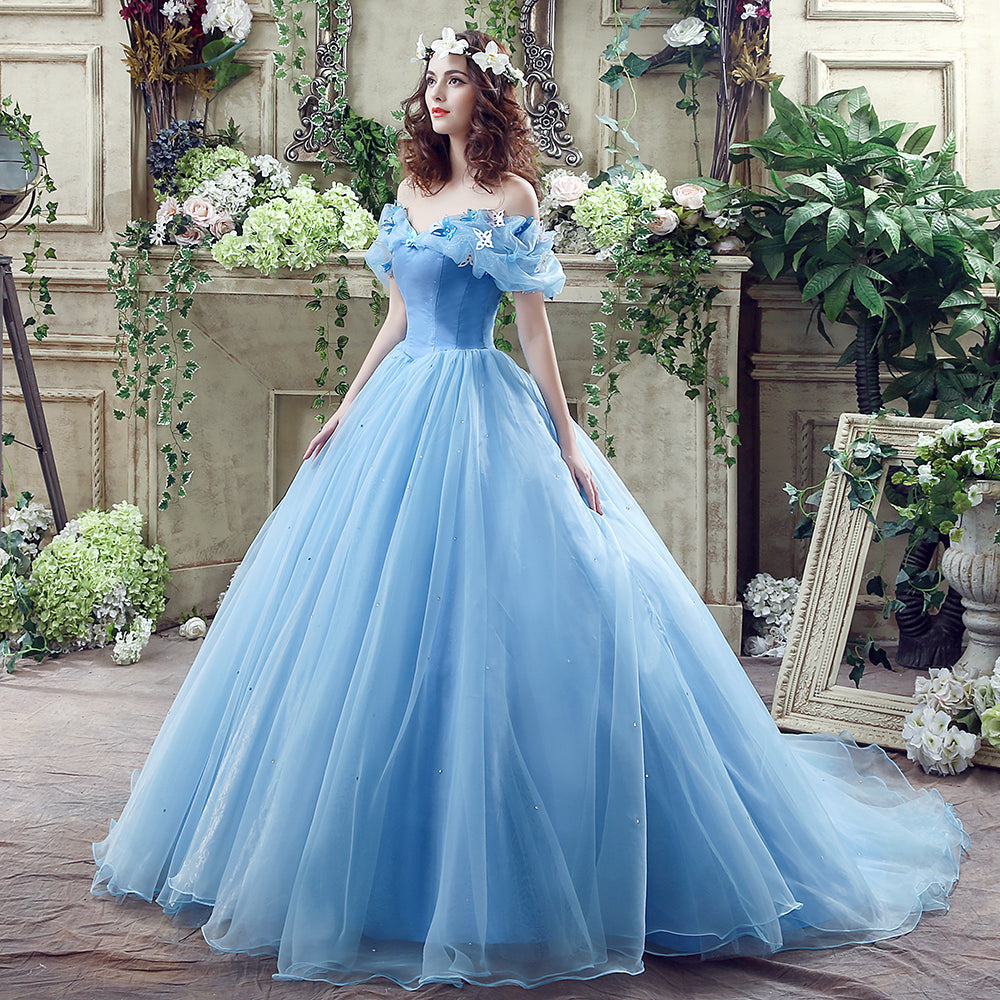 Woman in a blue gown standing in an elegant indoor setting with floral decorations.