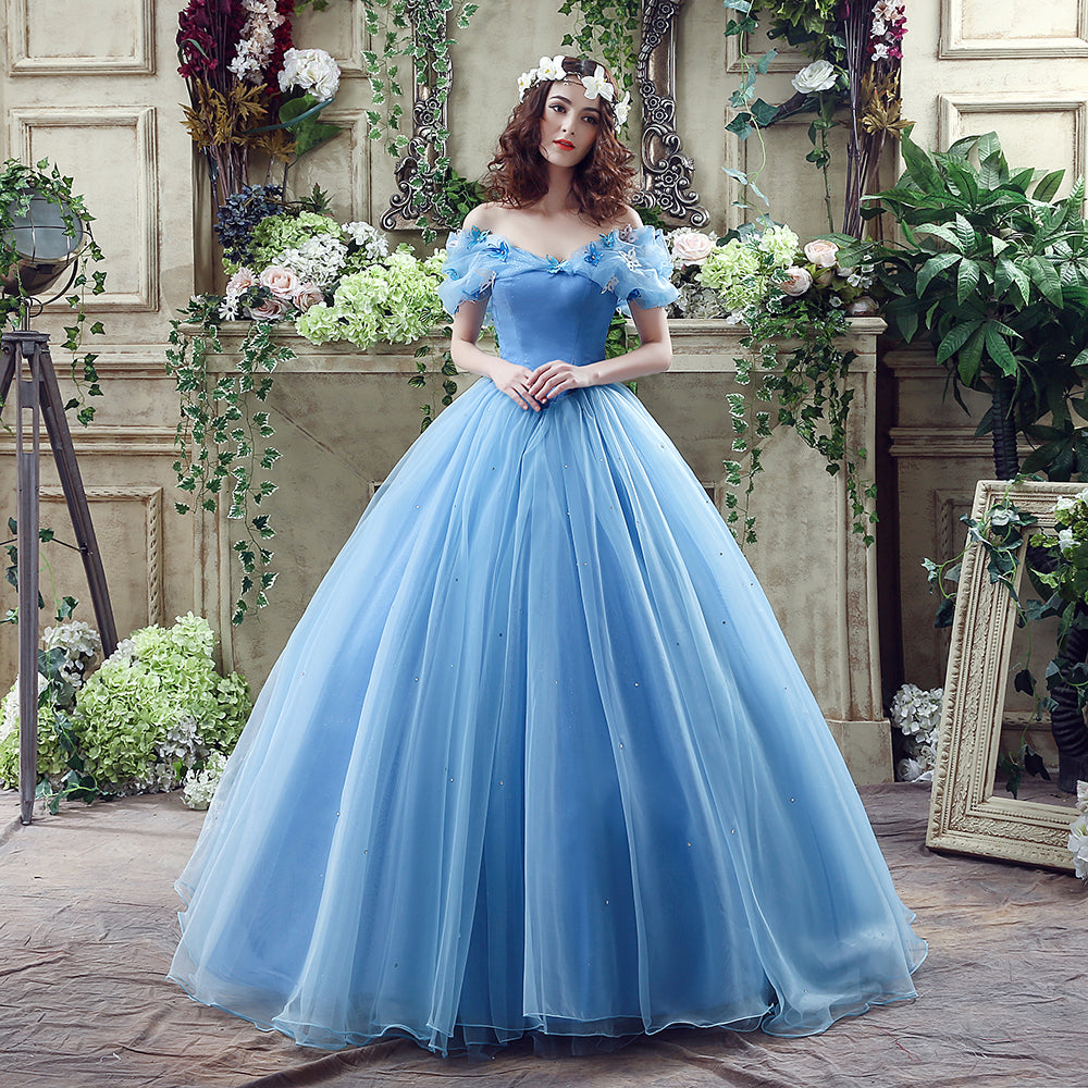 Woman in a blue gown standing in an ornate room with floral decorations.
