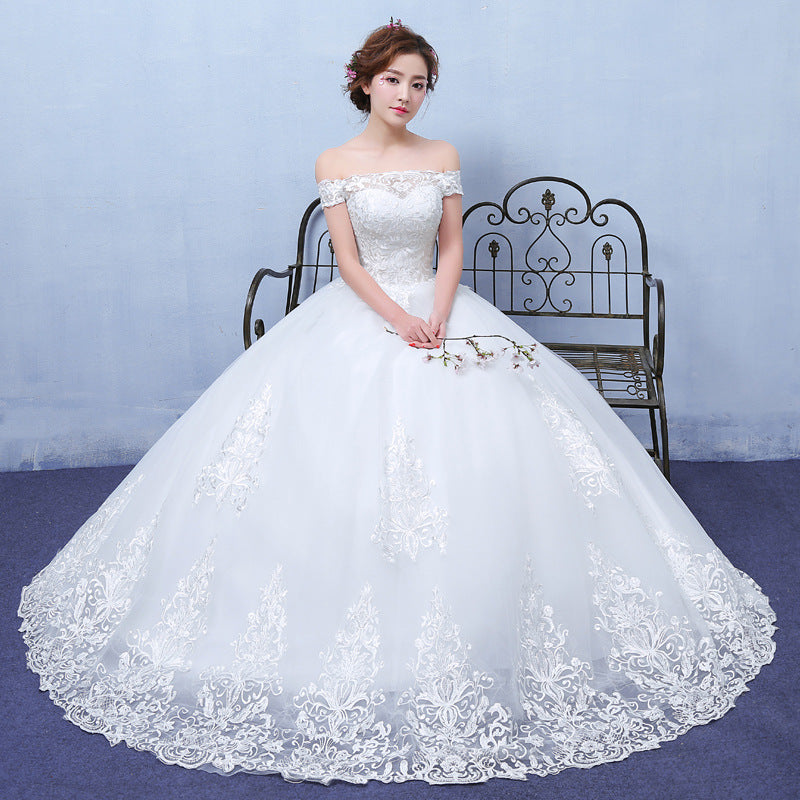 Woman wearing a white wedding dress with lace details in a studio setting.