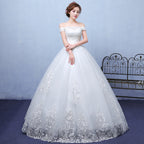 Woman wearing a white wedding dress with intricate lace details against a light blue background.