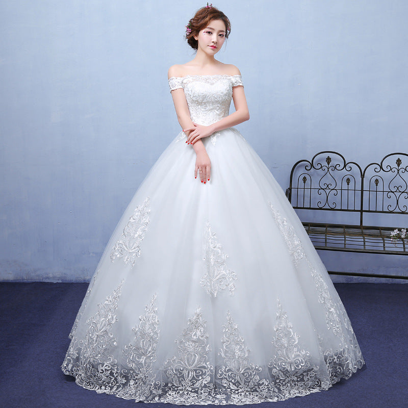 Woman wearing a white wedding dress with intricate lace details against a light blue background.
