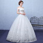 Woman wearing a white wedding dress with lace details against a light blue wall.