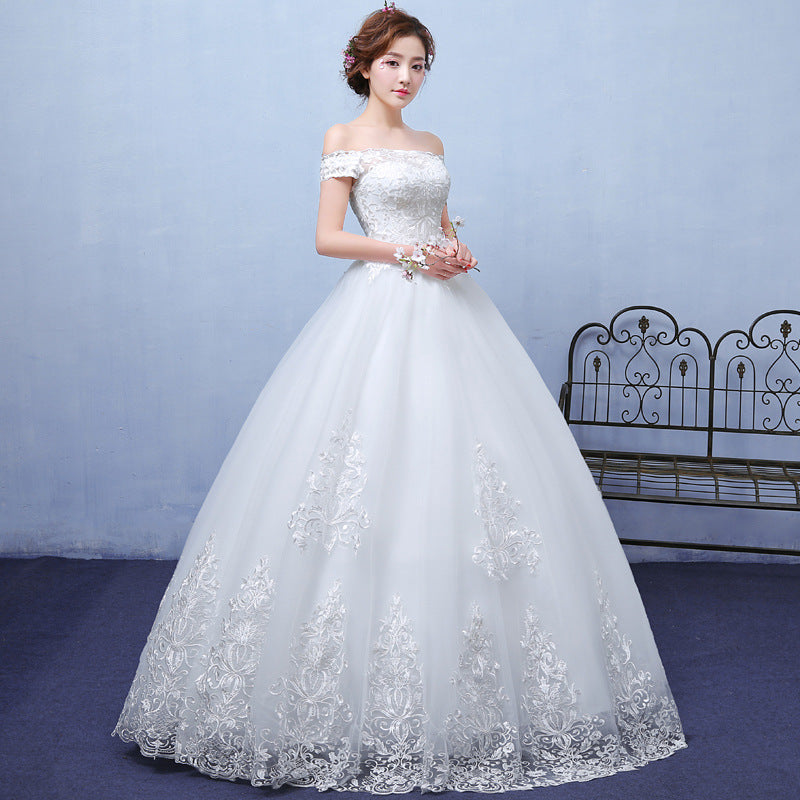 Woman wearing a white wedding dress with lace details against a light blue wall.