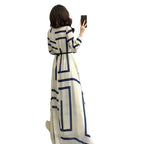 Woman wearing a long, patterned dress on a white background