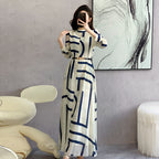 Woman taking a mirror selfie wearing a long dress with geometric pattern in a modern room.