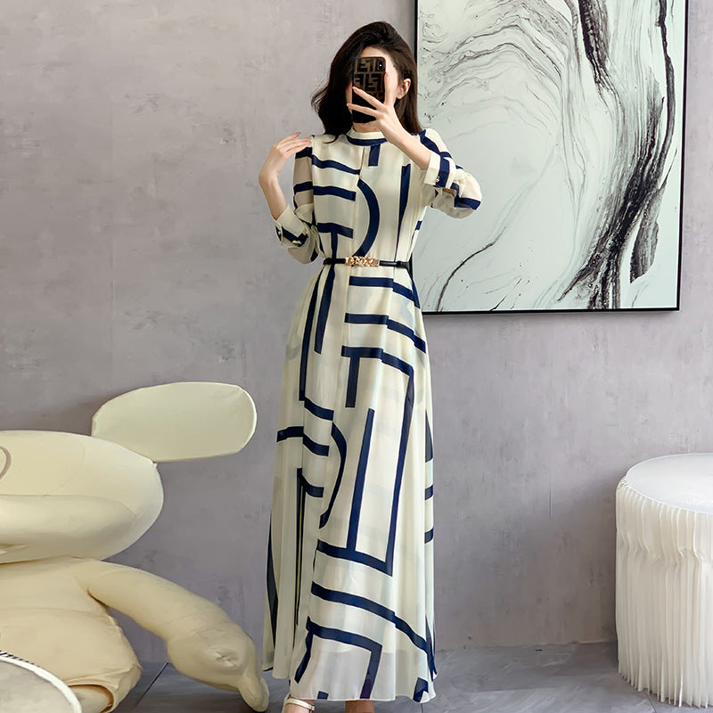 Woman taking a mirror selfie wearing a long dress with geometric pattern in a modern room.